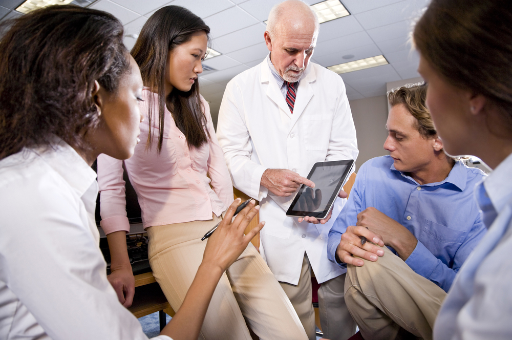 Professor Wearing Lab Coat Having Discussion With College Students